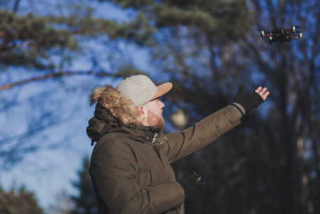 Profile of man holding drone outdoor. Pilot standing outdoor with quadrocopter. Electronics, modern technologiesの写真素材