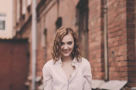 Outdoor lifestyle close up portrait of happy young woman in stylish casual outfit on the streetの写真素材