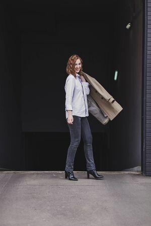 Beautiful happy woman in coat walking in city streetsの写真素材