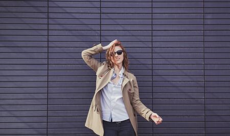 Smiling trendy model in sunglasses posing near wall. copy spaceの写真素材
