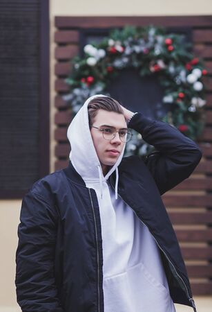 handsome man wears a bomber jacket and a white hoodie with a hoodの写真素材