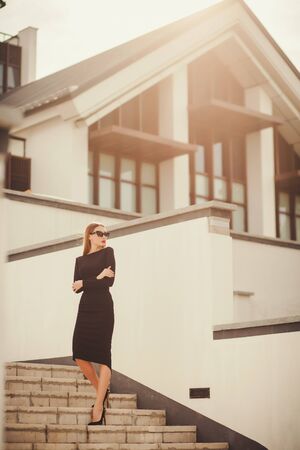 successful businessman in sunglasses full length stands on the background of office buildingの写真素材