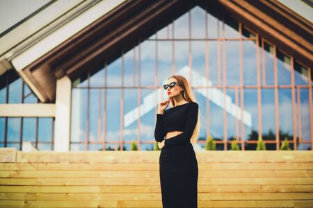 fashionable woman in sunglasses on the background buildings. looking away. cityscapeの写真素材