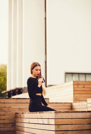 stylish girl in an elegant dress sitting in on the background of the cityの写真素材