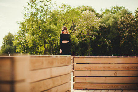 Fashionable young woman in sunglasses posing in the city alone