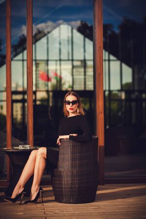 young woman in a black dress and shoes is resting in a cafe. summer terraceの写真素材