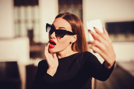 pretty woman in sunglasses taking selfies with her smart phoneの写真素材