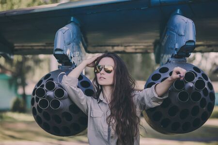 Portrait of young beautiful woman in sunglasses pilot in front of airplane.の写真素材