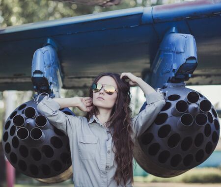 Portrait of beautiful fashion woman aviator near aircraftの写真素材