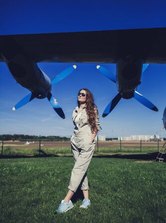Portrait of young beautiful woman pilot near airplane.の写真素材