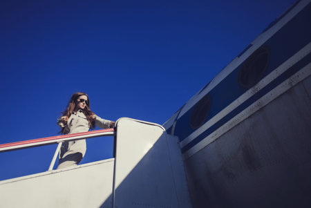 beautiful stylish woman in sunglasses posing on the background of the airplane