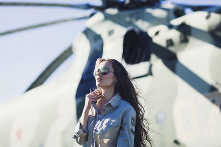 fashionable woman in Aviator glasses poses against the background of a helicopterの写真素材