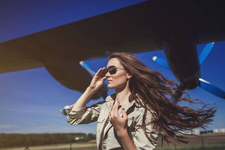 Portrait of a beautiful woman in Aviator glasses near aircraftの写真素材