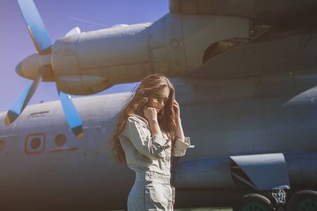 Portrait of fashion woman airplane pilot. Airplane on the backgroundの写真素材