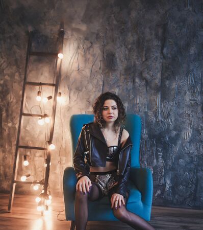 Young sexy woman in leather jacket posing on dark loft interiorの写真素材