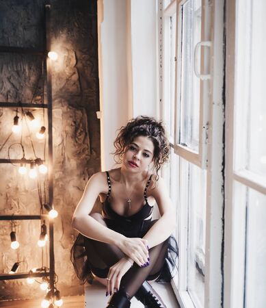 charming woman with curly hair sitting on a horse in the Studioの写真素材