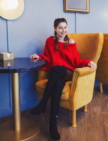 Happy young woman sitting on chair in cafeの写真素材