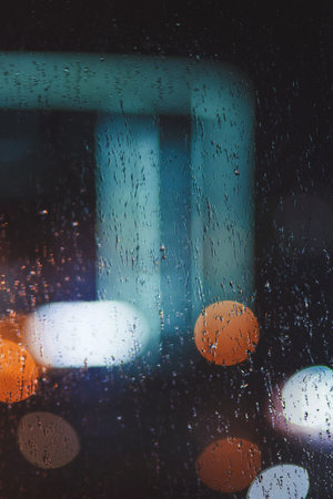 Abstract urban night light bokeh defocused background. raindrops on the glass
