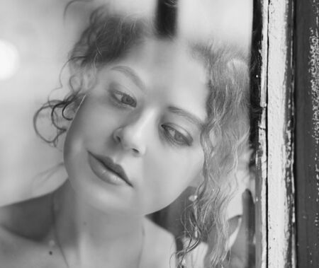 Portrait of a young calm woman in window.の写真素材