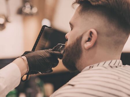 portrait of barber with comb and trimmer shaving manの写真素材