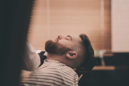 Handsome bearded man visiting hairstylist in barber shop.の写真素材