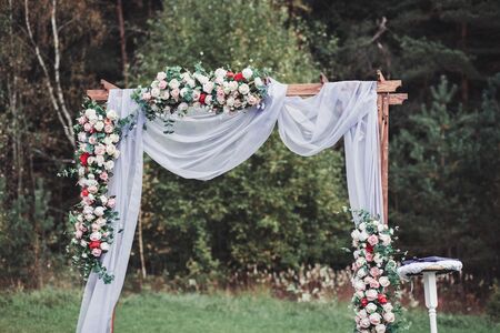 Beautiful wedding ceremony outdoors. Wedding arch made of cloth and flowersの写真素材