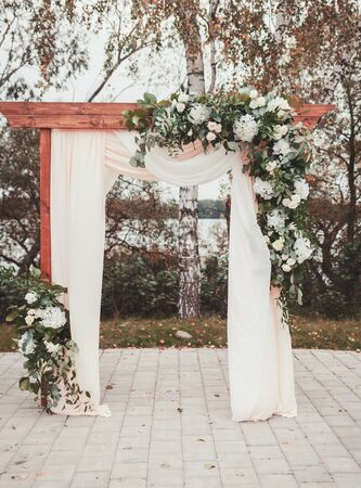 Wedding arch decorated with cloth and flowers outdoors. Beautiful wedding set up.の写真素材