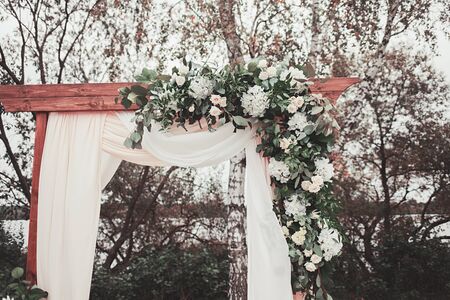 Floral arch with cloth and wooden elements at a rustic wedding ceremonyの写真素材