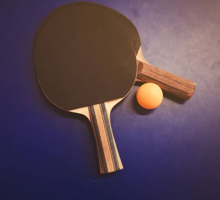 Two table tennis  rackets and ball on a blue table with net backgroundの写真素材