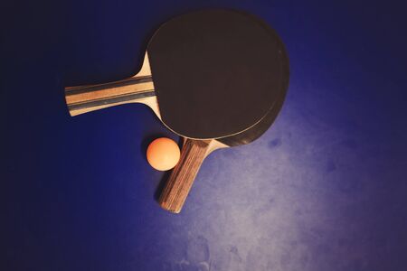 Blue table tennis . Two table tennis  rackets or paddles and ball on a blue tableの写真素材