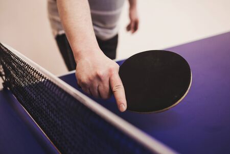 Tennis table player holds a table tennis racket in his handの写真素材