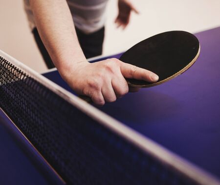 player's hand with a tennis racket on a blue table background.の写真素材