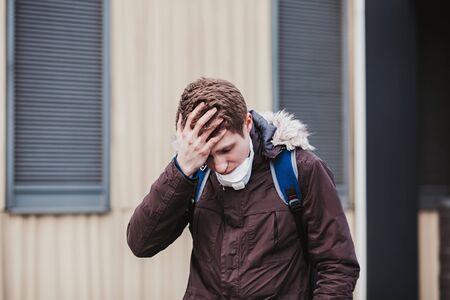 Sick European man in a protective mask in a public place. coronavirus anatomyの写真素材
