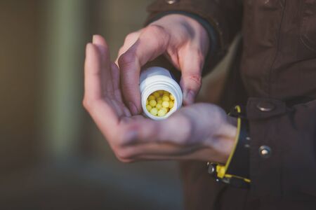 human hand holding yellow pills outdoors. Prevention of the spread of virus and pandemic COVID-19. Pills for viral diseases.の写真素材