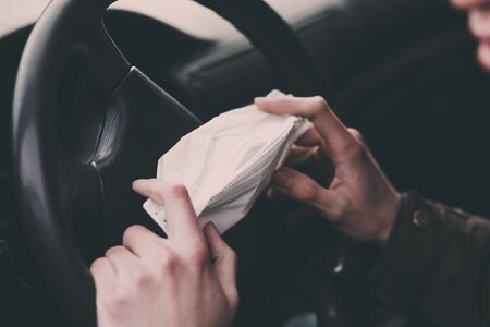 man drive car, holding in hands medical mask to protect from infection of viruses, pandemic, air pollution,の写真素材