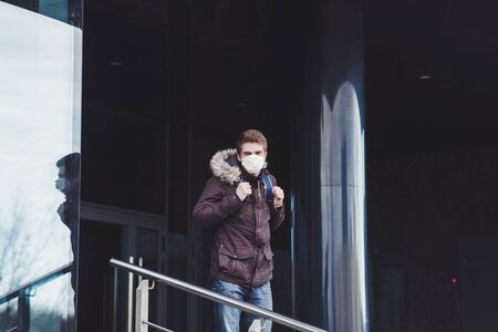 young european man in a protective mask leaves work. pandemic. corona-virusの写真素材