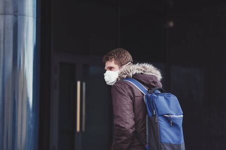 sick man with a backpack in a protective mask enters the hospital buildingの写真素材