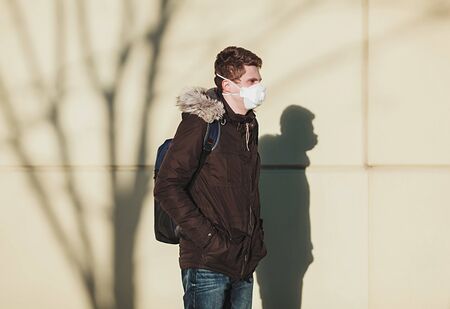 Man with mask to protect her from Corona virus standing next to wall. Corona virus pandemic. COVID-19の写真素材