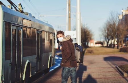 Ill man wearing protective mask against transmissible infectious diseases and as protection against the flu near public transport. New coronavirus 2019-nCoVの写真素材