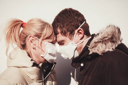 Loving couple wearing a protective face mask and staring at each other's eyes, pandemicの写真素材