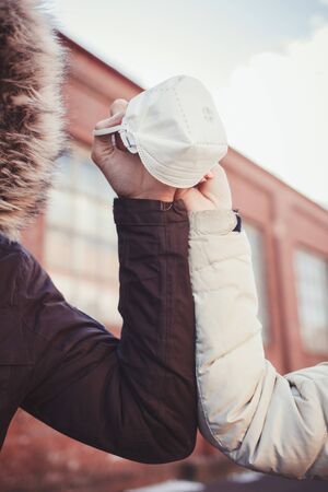 couple of friends greet each other with their elbows during a coronavirus. medical mask in the hands of a coupleの写真素材