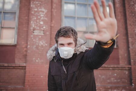 European man wearing mask for protect pm2.5 and show stop hands gesture for stop corona virus outbreak. Coronavirus and Air pollution pm2.5 conceptの写真素材