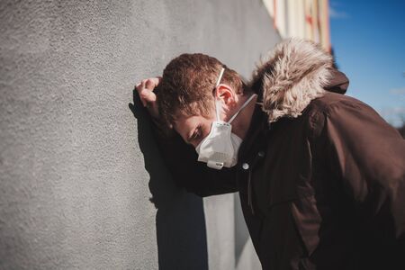 Ill man in protective medical mask near wall. coronavirus pandemicの写真素材
