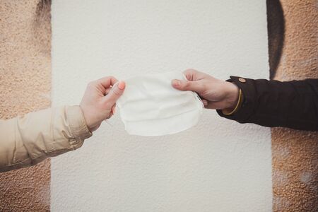 protective medical mask. prevention from coronavirus. hands holding the mask against the wallの写真素材