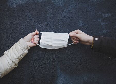 hands holding a protective medical mask against the wall. prevention from coronavirus.の写真素材