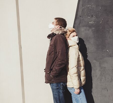 Woman and a man with masks near wall. Protection against Coronavirus COVID-19 (SARS-CoV-2) and other infectious diseases.の写真素材