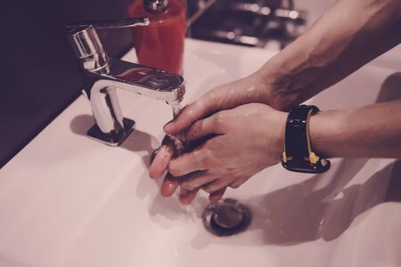 man washes his hands in the bathroom during the coronavirus pandemic. the concept of hygieneの写真素材
