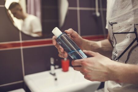 man with a bottle of liquid antibacterial soap in the bathroom . prevention of bacterial diseases and virusesの写真素材