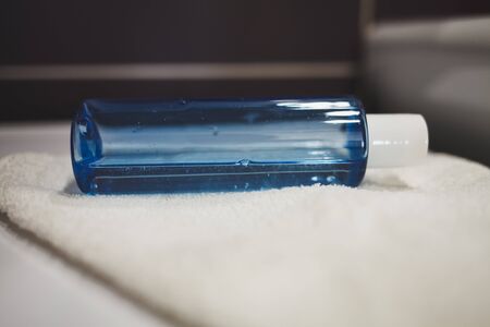 plastic blue bottle of antibacterial liquid soap is lying on a white towel in the bathroomの写真素材
