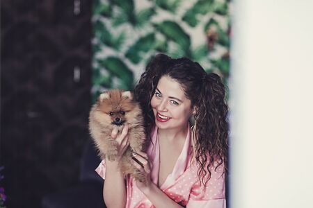 Domestic portrait cute woman and little spitz in roomの写真素材